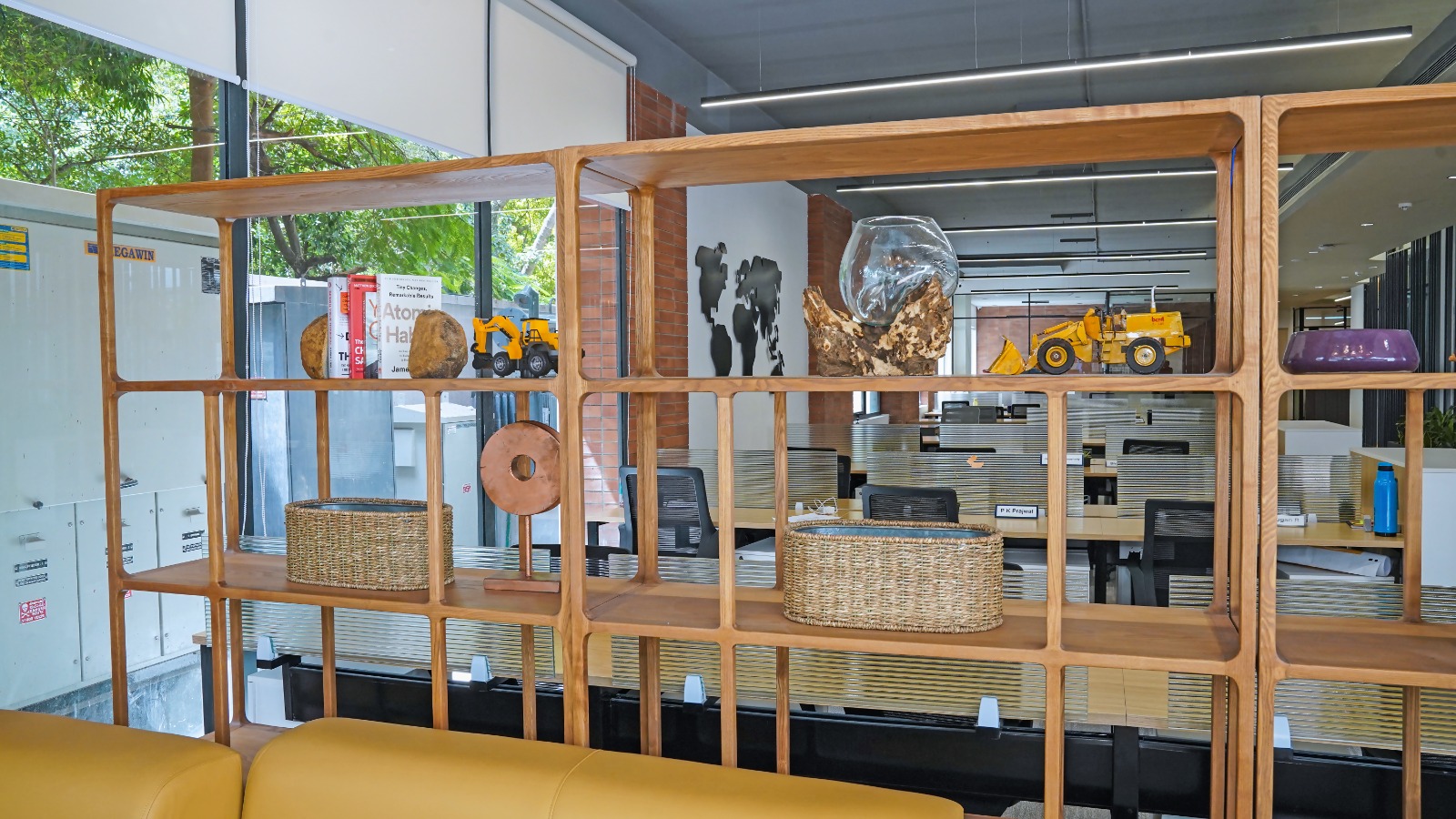 Breakout and collaboration zone with soft seating and an open timber shelving screen at Capstone House Ground Floor office space Bangalore