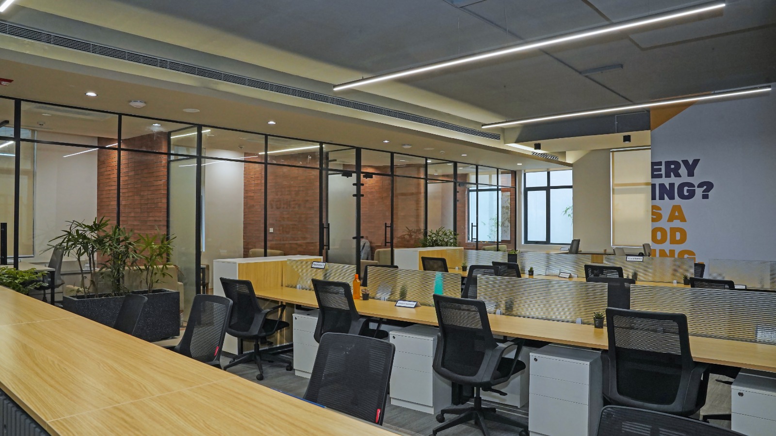 Glass-partitioned private cabins running alongside open workstations, showing the zoning of the plug and play office floor at Capstone House